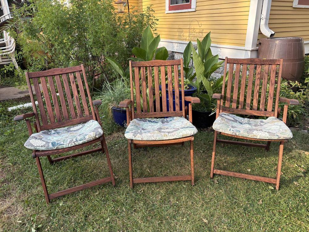 Three oak folding chairs we sanded back and refinished, set out on a lawn