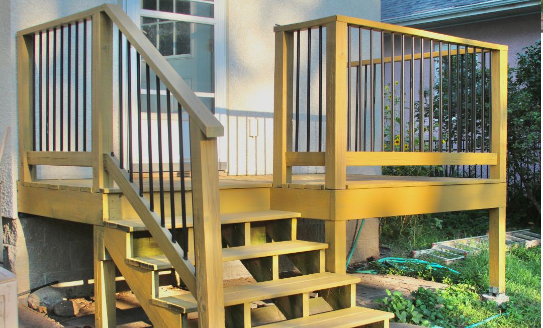 The same deck after stripping, sanding and staining — even colour across the boards, railings and stairs