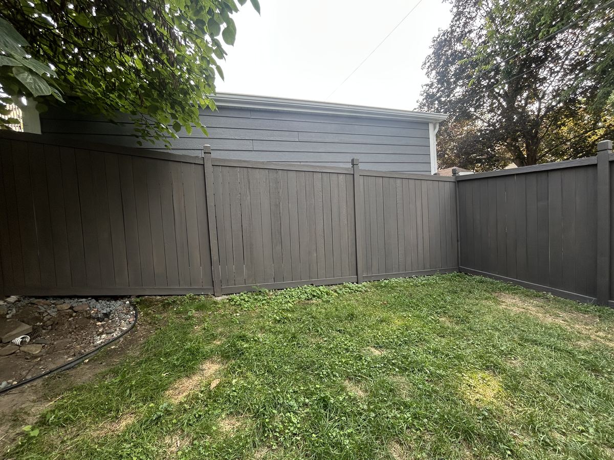 The same fence corner after cleaning and staining, finished in an even charcoal grey including the rails and post caps