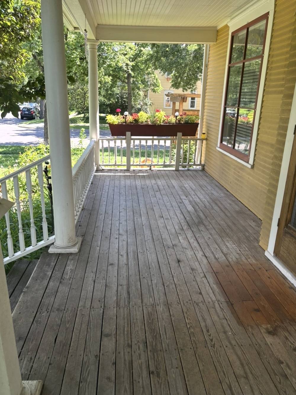 A Victorian front porch with tongue-and-groove floorboards gone silver-grey and blotchy, before restoration